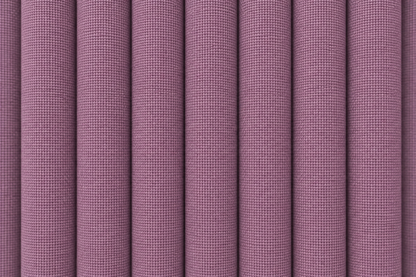 A close-up of pleated fabric with a fine woven texture in a muted dusty mauve or lavender-purple color.