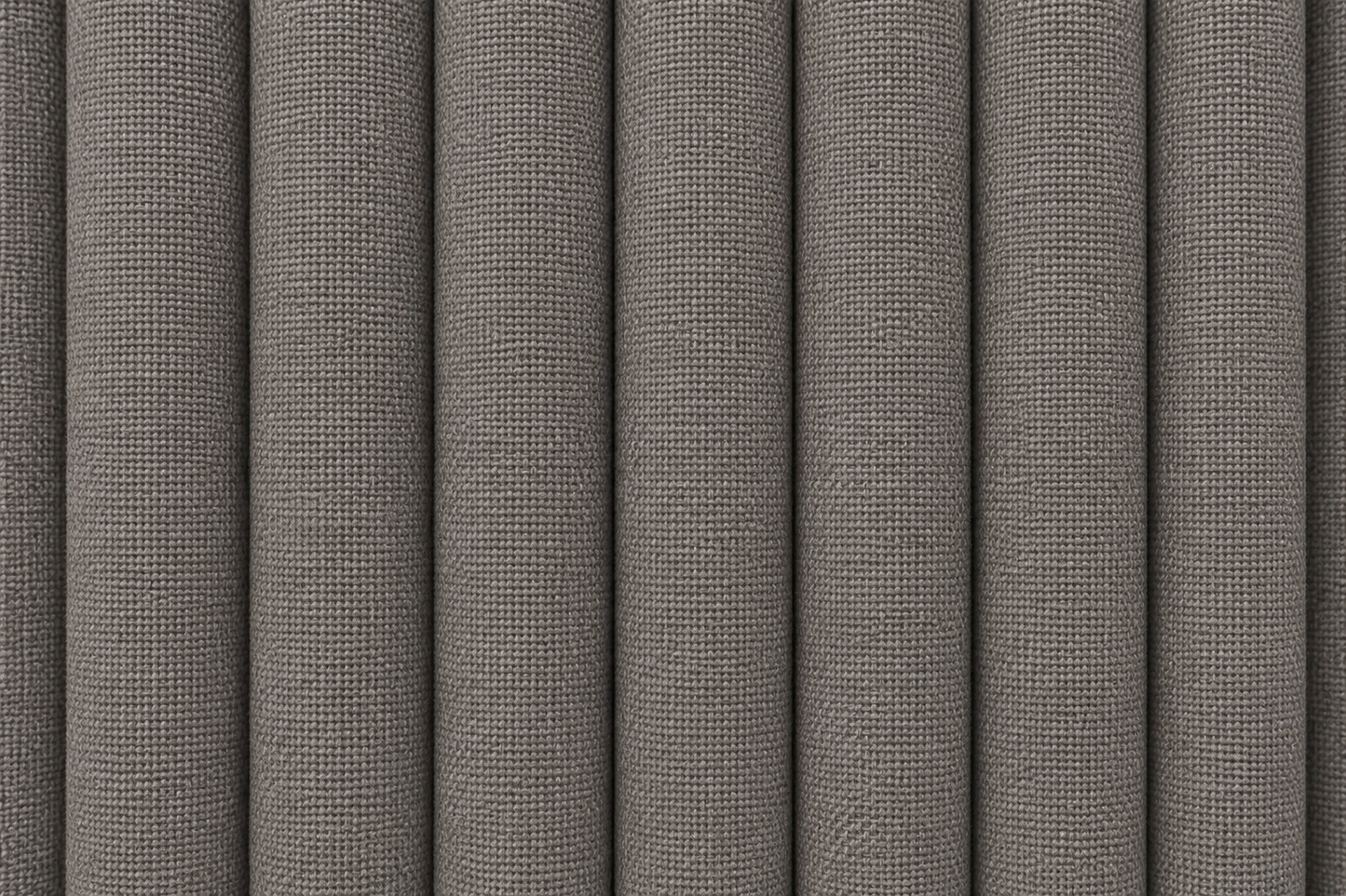 A close-up of vertically pleated fabric or upholstery material in a medium warm gray color, showing a fine woven texture.