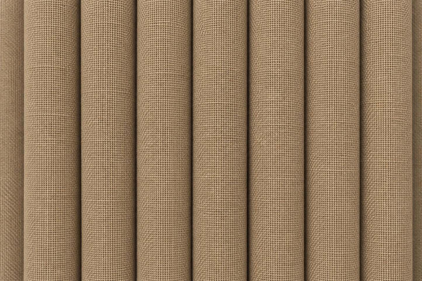 Close-up of a woven fabric texture in a warm tan or beige color, shown with vertical folds.