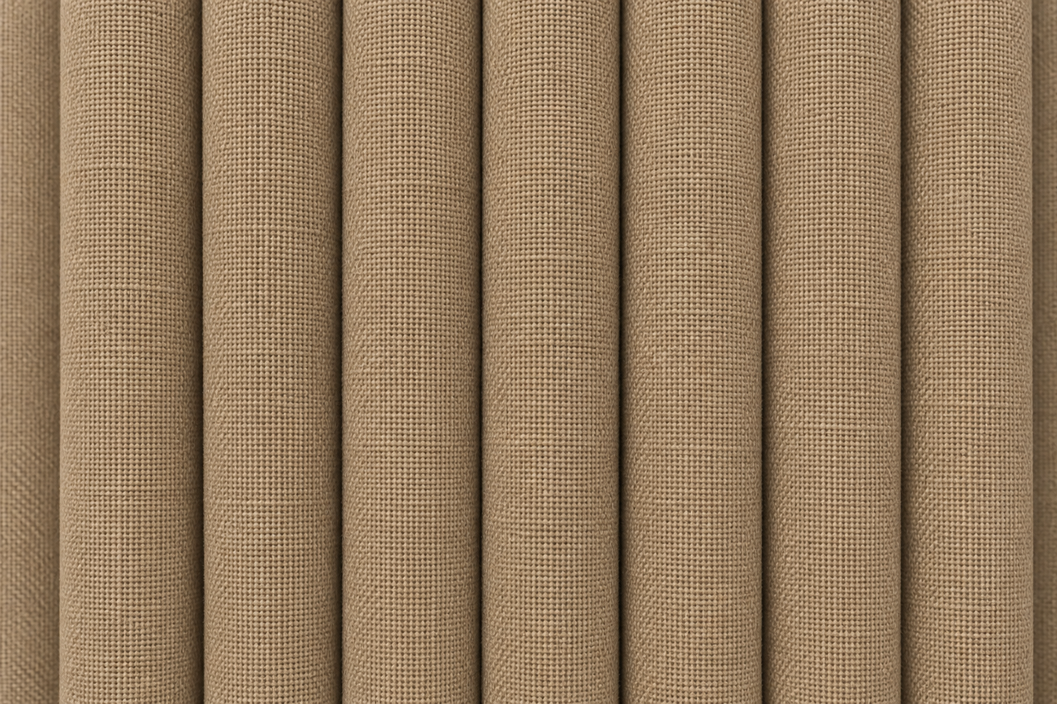 Close-up of a woven fabric texture in a warm tan or beige color, shown with vertical folds.