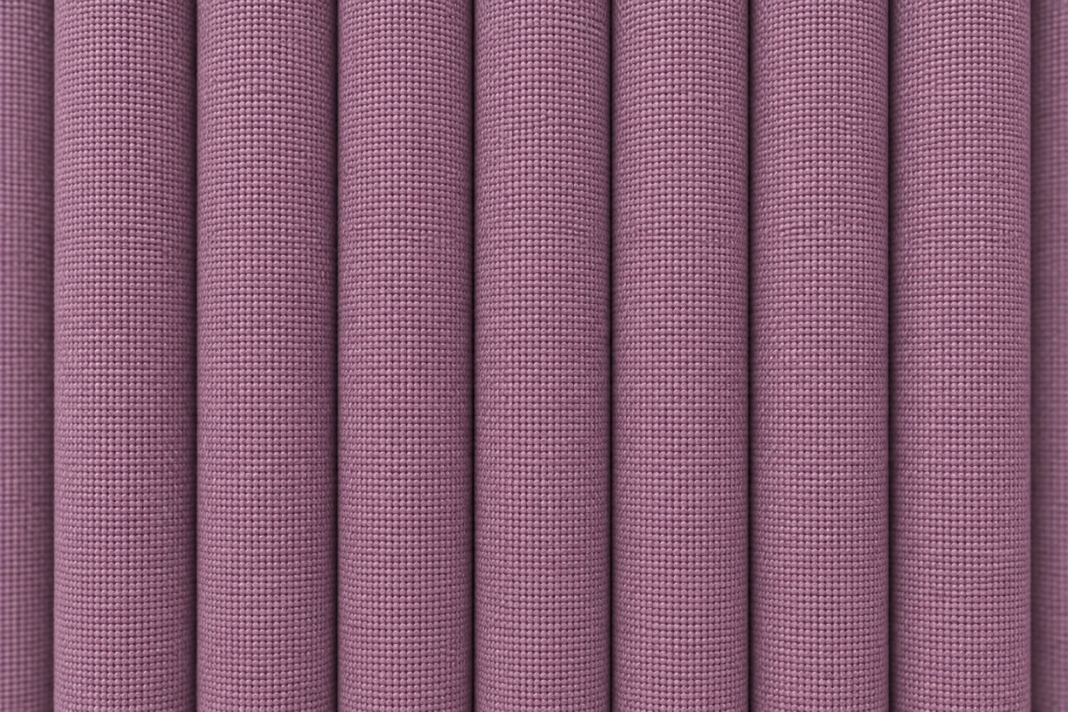 A close-up of pleated fabric with a fine woven texture in a muted dusty mauve or lavender-purple color.